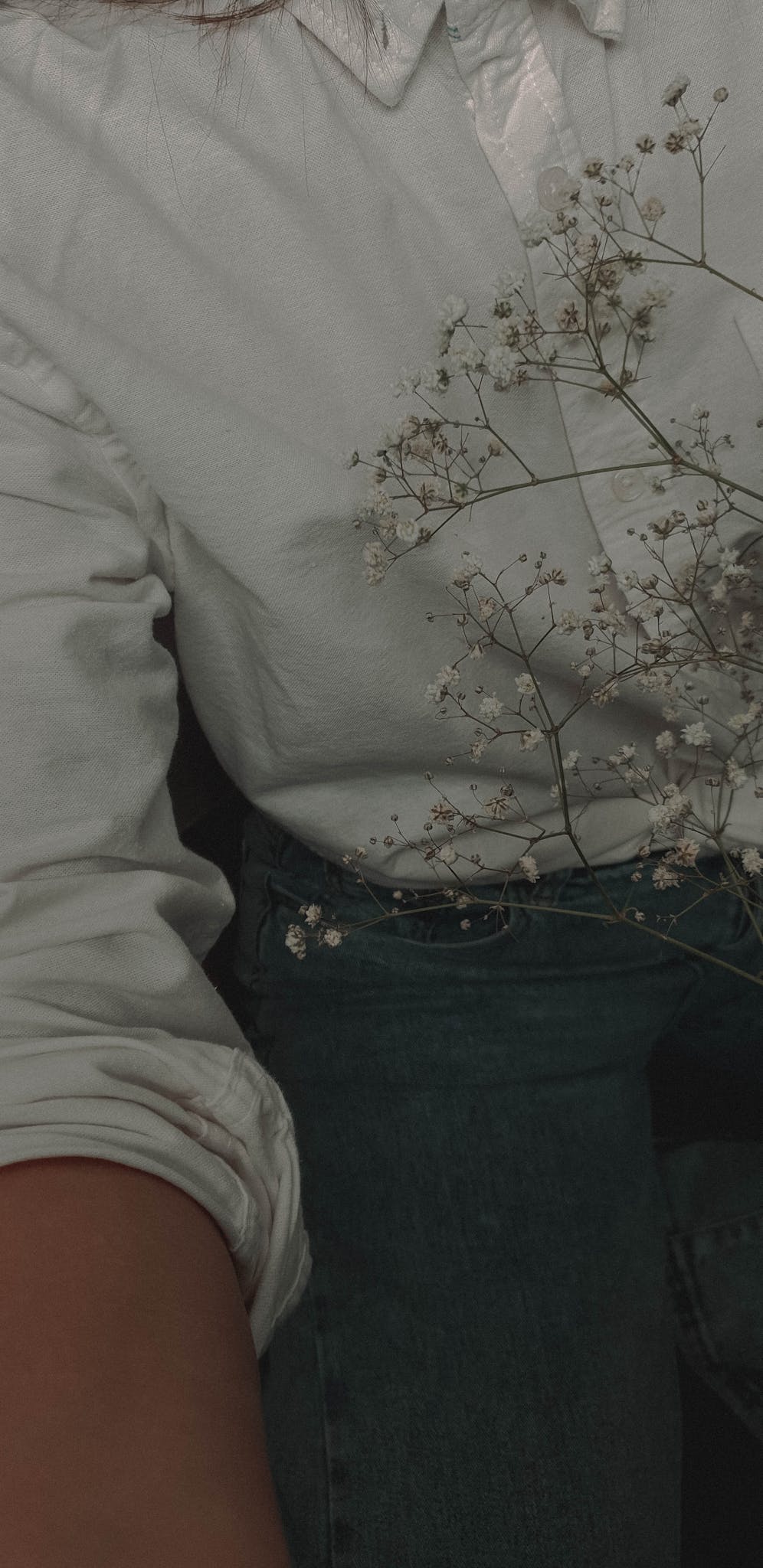 A stylish close-up of baby's breath flowers paired with casual denim and a white shirt.